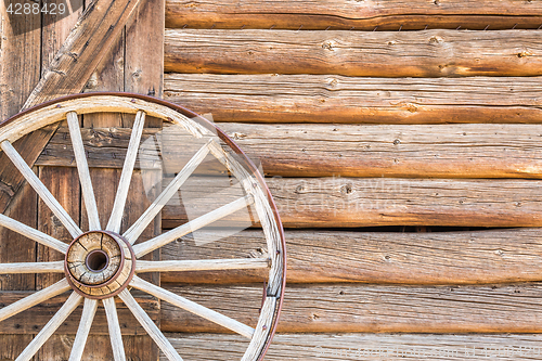 Image of Abstract of Vintage Antique Log Cabin Wall and Wagon Wheel.