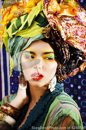 Image of beauty bright woman with creative make up, many shawls on head l