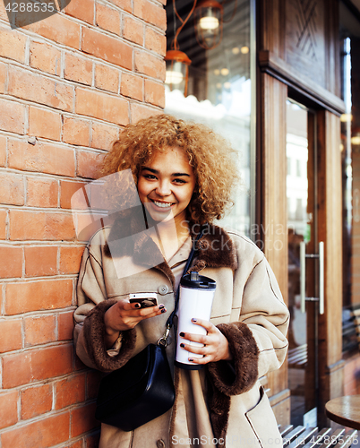 Image of young pretty african american women drinking coffee outside in c