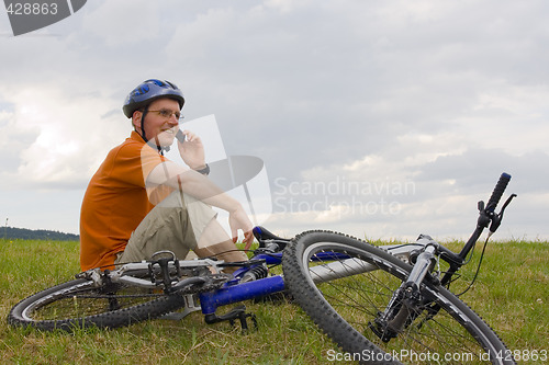 Image of Man with mountain bike talking on cell phone