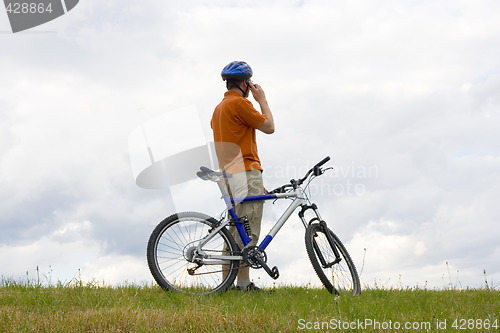Image of Man with mountain bike talking on cell phone