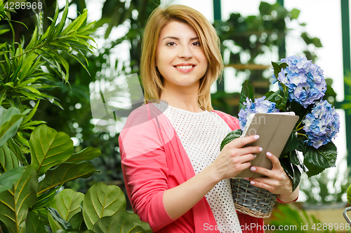 Image of Florist with bouquet holds tablet