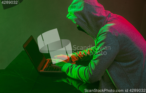 Image of Hooded computer hacker stealing information with laptop