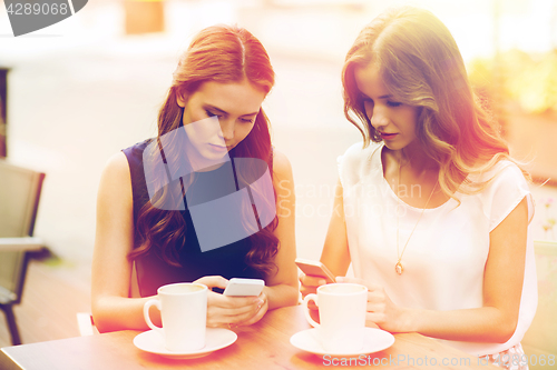 Image of women with smartphones and coffee at outdoor cafe