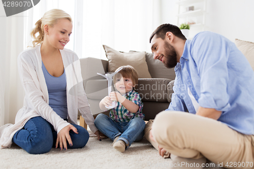 Image of happy family playing with toy wind turbine