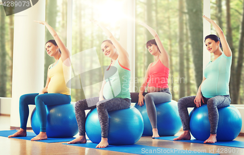 Image of happy pregnant women exercising on fitball in gym