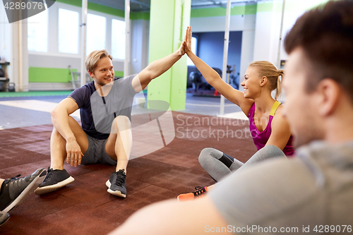 Image of group of happy friends making high five in gym