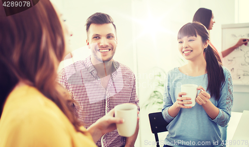 Image of happy creative team drinking coffee at office