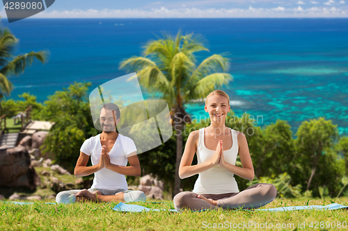 Image of happy couple doing yoga and meditating outdoors
