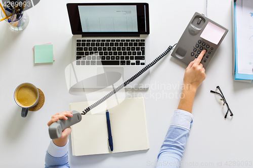 Image of businesswoman calling on phone at office table