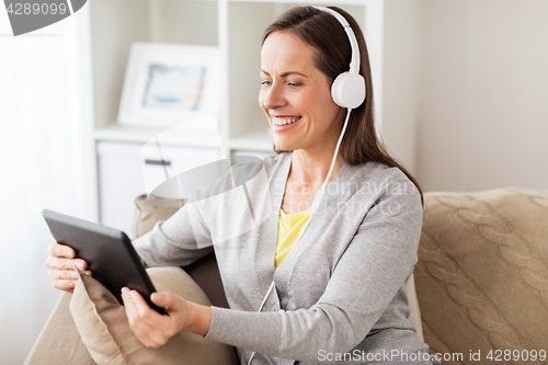 Image of happy woman with tablet pc and headphones at home