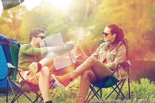 Image of happy couple clinking drinks at campsite tent