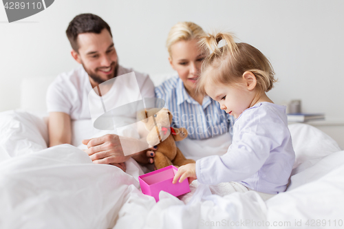 Image of happy family with gift box in bed at home