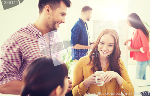 Image of happy creative team drinking coffee at office