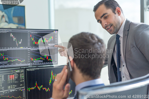 Image of Stock brokers looking at computer screens, trading online.