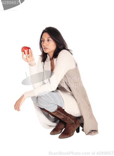 Image of Woman crouching looking at a red apple.