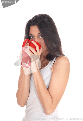 Image of Hispanic woman drinking from a red mug.