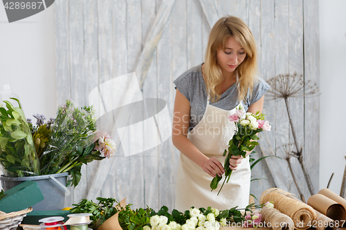 Image of Young blond florist makes bouquet