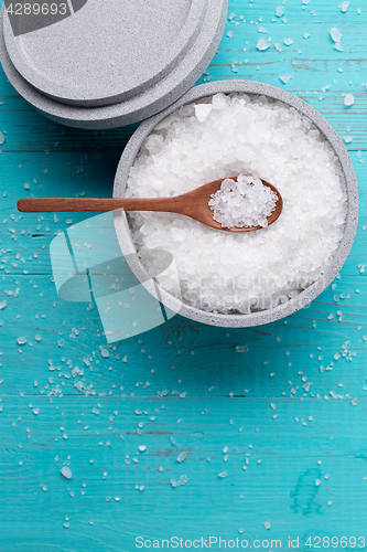 Image of Sea salt in an stone bowl with small wooden spoon on a blue wooden table