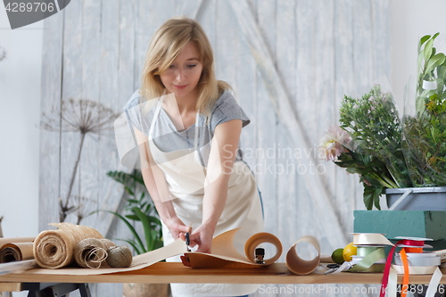 Image of Blonde florist cuts wrapping paper