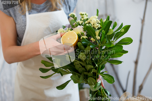 Image of Woman composes bouquet with lemon