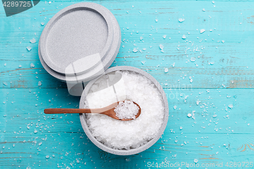 Image of Sea salt in an stone bowl with small wooden spoon on a blue wooden table