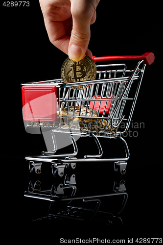 Image of hand throws a bitcoin into trolley.