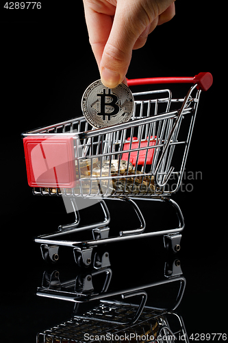 Image of hand throws a bitcoin into trolley.