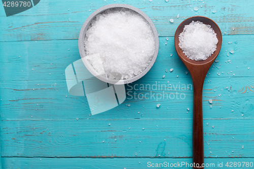 Image of sea salt in bowl and in spoon on wooden background