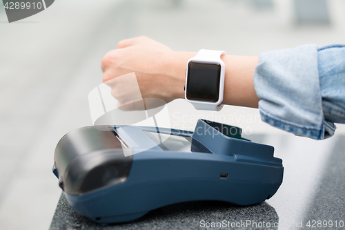 Image of Female customer paying through smart watch by NFC