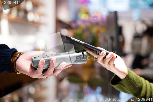 Image of Woman paying with NFC technology on mobile phone