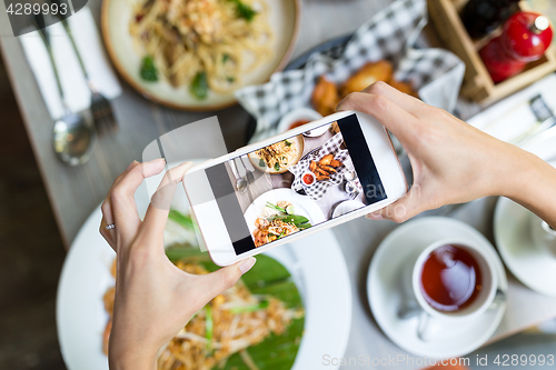 Image of Woman taking photo on cellphone on dish