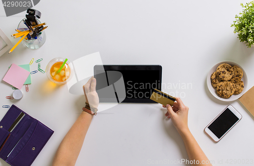 Image of hands with tablet pc and credit card at table