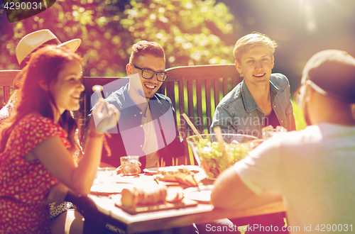 Image of happy friends having dinner at summer garden party