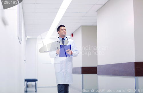Image of doctor with clipboard walking along hospital