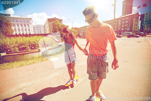 Image of teenage couple riding skateboards on city street