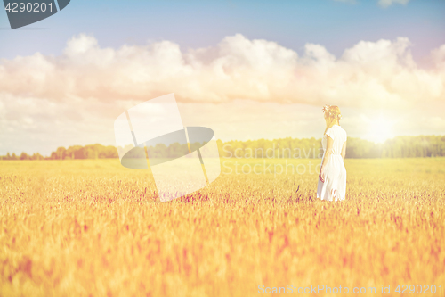 Image of happy young woman in flower wreath on cereal field