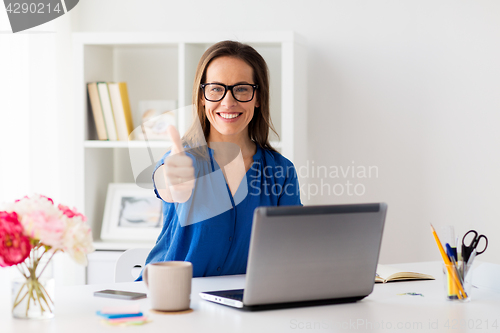 Image of woman with laptop showing thumbs up at office