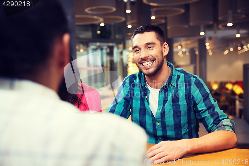 Image of happy man meeting with friends at restaurant