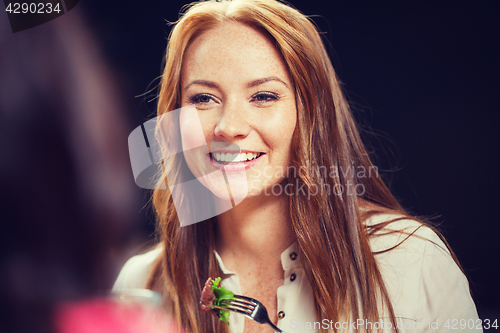 Image of happy young woman having dinner at restaurant