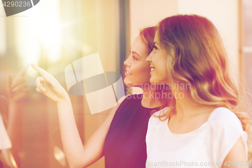 Image of happy young women pointing finger to shop window