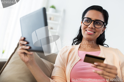 Image of happy woman with tablet pc and credit card at home