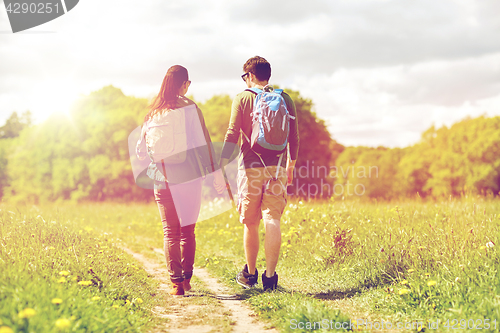 Image of happy couple with backpacks hiking outdoors