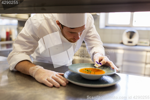 Image of male chef decorating dish with pansy flower