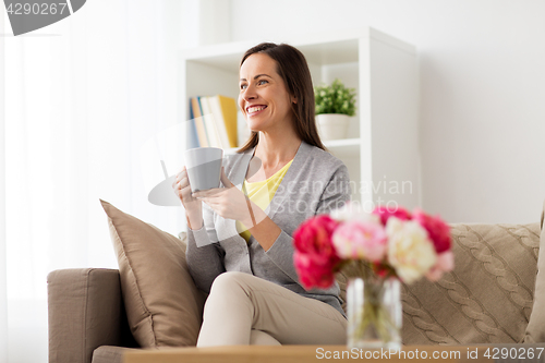Image of happy woman drinking tea or coffee at home