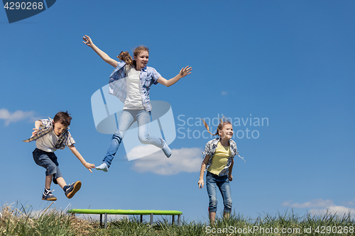 Image of Brother and sisters playing on the field at the day time.