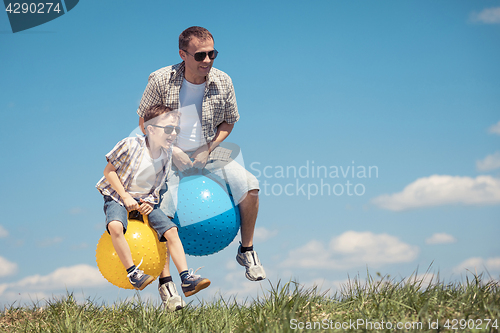 Image of Father and son playing on the field at the day time.