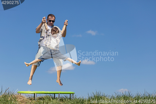 Image of Father and son playing on the field at the day time.