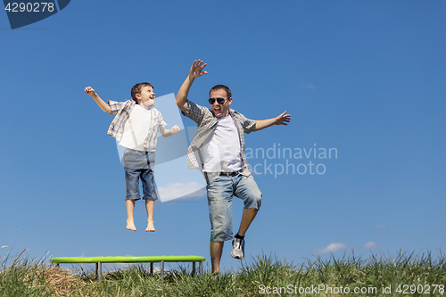 Image of Father and son playing on the field at the day time.