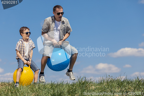 Image of Father and son playing on the field at the day time.